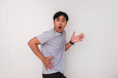 Asyalı komik bir genç adam beyaz arka planda izole edilmiş şok edici bir jestle şaşırmış bir yüz ifadesi sergiliyor. Terfi, tepki ya da reklam kavramları için mükemmel.