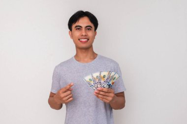 Elinde parayı gösteren gülümseyen Asyalı genç bir adam, beyaz arka planda soyutlanmış. Finans, promosyon, başarı ve Güneydoğu Asya reklam temaları için mükemmel bir imaj