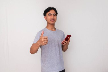 Beyaz arka planda izole edilmiş akıllı telefonu tutan gülümseyen Asyalı genç adam. Terfi için, mobil reklamlar için ya da teknolojiyle ilgili kampanyalar için mükemmel.