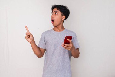 Genç adam işaret ederken heyecanla telefonunu tutuyor..