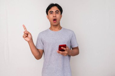 Genç adam işaret ederken heyecanla telefonunu tutuyor..