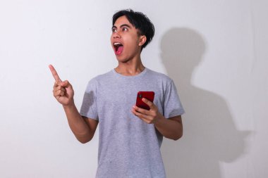 Genç adam işaret ederken heyecanla telefonunu tutuyor..