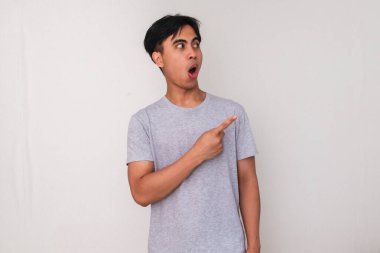 Yüzünde tuhaf bir ifade olan, beyaz arka planda izole edilmiş, promosyon veya reklam içeriği için mükemmel genç Asyalı bir adamın portresi.