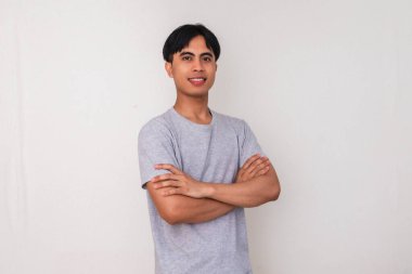 Kollarını kavuşturup kameraya temiz beyaz arka planda bakan kendine güvenen genç Asyalı bir adamın portresi iş, promosyon ya da reklam teması için mükemmel.