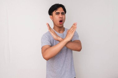 Beyaz bir arka planda izole bir şekilde kameraya bakarken el hareketi yapan Asyalı genç bir adamın portresi. Uyarı ve bilinçlendirme kampanyaları için mükemmel