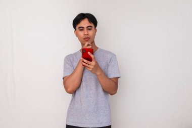 Akıllı bir jest yaparken akıllı telefon kullanan genç bir Asyalı 'nın portresi, beyaz arka planda izole edilmiş, reklamcılık veya yaratıcı içerik için mükemmel.