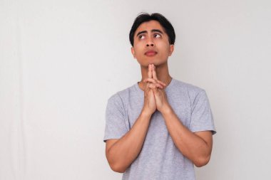 Asyalı genç bir adamın portresi, eli çenesinde ve gözlerinde, beyaz arka planda soyutlanmış, yaratıcı reklam veya konsept çizimi için mükemmel bir şekilde ciddi bir şekilde düşünüyor.