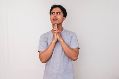 Asyalı genç bir adamın portresi, eli çenesinde ve gözlerinde, beyaz arka planda soyutlanmış, yaratıcı reklam veya konsept çizimi için mükemmel bir şekilde ciddi bir şekilde düşünüyor.