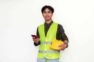 Gülümseyen genç Asyalı mühendis kendine güvenen bir akıllı telefon tutuyor. Modern teknolojiye sahip bir profesyonelin portresi, farklı endüstri kavramları için idealdir.