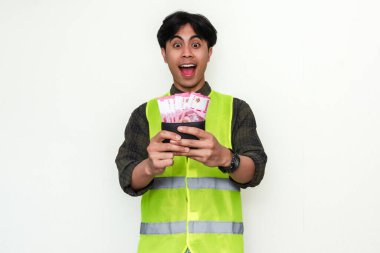 Mutlu Asyalı inşaat işçisi para dolu cüzdana bakıp heyecanlı bir yüz ifadesi göstererek beyaz arka planda izole edilmiş bir şekilde hayrete düştü. Maaş, ödül ve başarı temaları için ideal