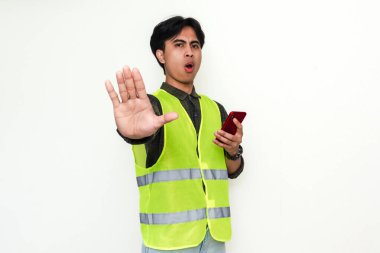 Asyalı inşaat işçisi akıllı telefonu tutuyor ve beyaz arka planda izole bir şekilde el hareketini durduruyor.