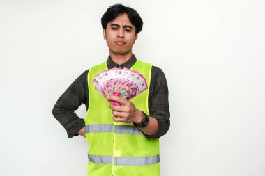 Asyalı inşaat işçisi, beyaz arka planda izole edilmiş ciddi bir düşünce jestiyle eline bakıyor. Maaş, bütçe veya finansal planlama gibi konular için harika