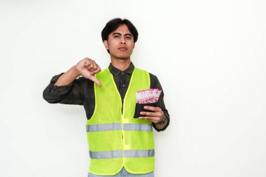 Asyalı inşaat işçisi elinde cüzdan tutarken parmaklarını gösteriyor. Finansal mücadeleyi ya da onaylanmamayı temsil eden güçlü bir görsel