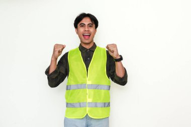 Heyecanlı Asyalı inşaat işçisi yumruklarını sıkarak başarıyı kutluyor. Beyaz arka plandaki portre, reklamlar, endüstri veya kariyer motivasyonu kavramları için mükemmel.