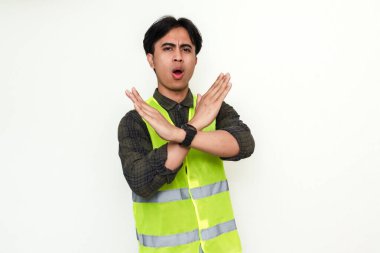 Asyalı ciddi bir inşaat işçisinin portresi izole edilmiş beyaz bir arkaplanda el hareketi gösteriyor.