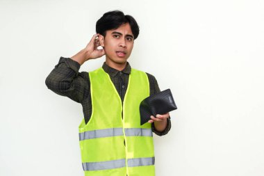 Zavallı Asyalı inşaat işçisi beyaz arka planda izole edilmiş, kafası karışmış bir ifadeyle boş cüzdanına bakıyor.