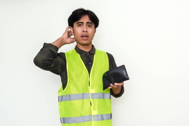 Zavallı Asyalı inşaat işçisi beyaz arka planda izole edilmiş, kafası karışmış bir ifadeyle boş cüzdanına bakıyor.