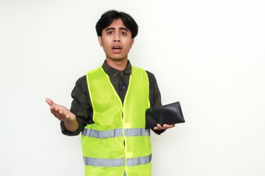Zavallı Asyalı inşaat işçisi beyaz arka planda izole edilmiş, kafası karışmış bir ifadeyle boş cüzdanına bakıyor.