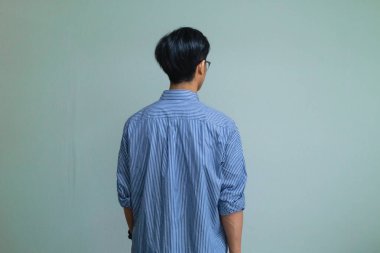 İzole edilmiş bir arka planda duran Asyalı genç bir adamın arka plan portresi