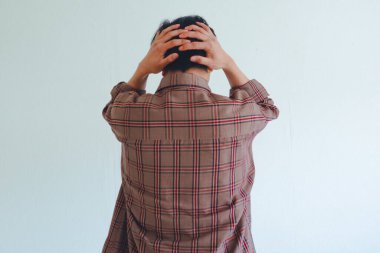 Stresli Asyalı adam kafasını arkadan tutuyor. İzole edilmiş beyaz arka planda hayal kırıklığı ve endişe gösteriyor. Duygusal bakış açısı.