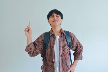 Sırt çantası takan gülümseyen erkek öğrencinin portresi beyaz arka planda gururlu bir ifade sergiliyor.