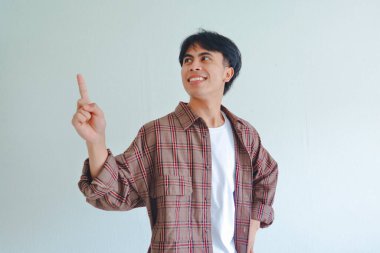 Neşeli bir gülümseme ile yukarı bakan mutlu Asyalı adam, sade bir arka planda izole edilmiş, terfi için mükemmel.