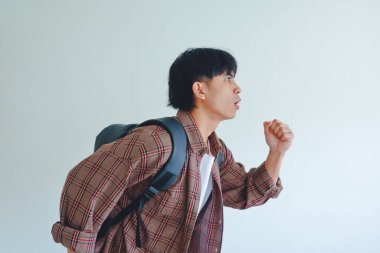 Sırt çantalı genç Asyalı bir erkek öğrenci, enerjik bir ifade takınıyor, beyaz arka planda izole edilmiş, eğitim veya yaşam tarzı konsepti için mükemmel.