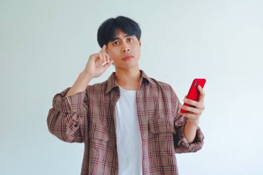 Asyalı bir adam ciddi düşünen bir yüze sahip, beyaz arka planda izole edilmiş, odaklanma ve konsantrasyon gösteriyor..