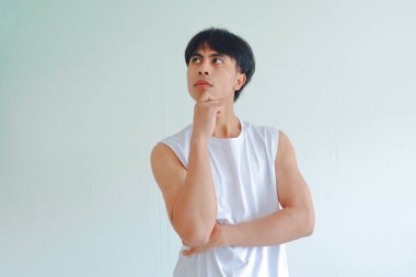 Güneydoğu Asyalı genç bir adamın portresi, eli çenesinde, düşünceli bir duruşta, beyaz arka planda izole edilmiş, düşünce ve tefekkürü temsil eden
