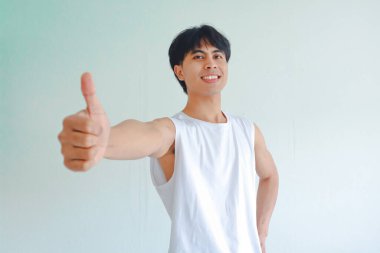 Güneydoğu Asyalı neşeli genç bir adamın portresi. Beyaz arka planda izole bir şekilde kameraya güvenle gülümsüyor. Başarı kavramı, pozitiflik, onay