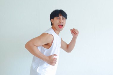 Heyecanlı bir Asyalının portresi beyaz arka planda izole bir şekilde koşan bir jest yapıyor. Motivasyonu, başarıyı ve aktif yaşam tarzını temsil eden enerjik yüz ifadesi