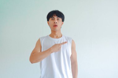 Beyaz arka planda izole edilmiş, şok olmuş bir ifadeyle yan tarafı gösteren, şaşırmış, genç Asyalı bir adamın komik portresi. Fitness, promosyon veya reklam konsepti için mükemmel.