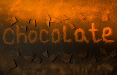 bir güneş ışını ile siyah grafit arka plan üzerine çikolata ve çikolata tozu parçaları nın eklenmesi ile kakao tozu ndan yapılmış yazıt çikolata