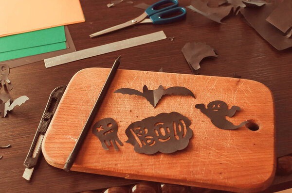 Ремесла для празднования Хэллоуина концепции. Черная летучая мышь и призрачные фигуры, вырезанные из черной бумаги на деревянной доске. Вид сверху
