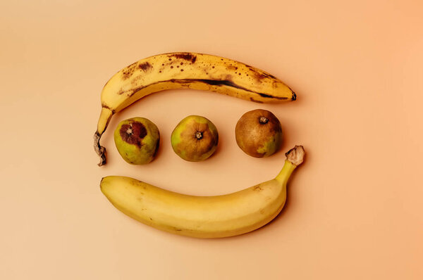 Ugly fruit modification of bananas from ripe to more spoiled brown with spots and decayed limes isolated. The concept of fruit is not salable for supermarkets.