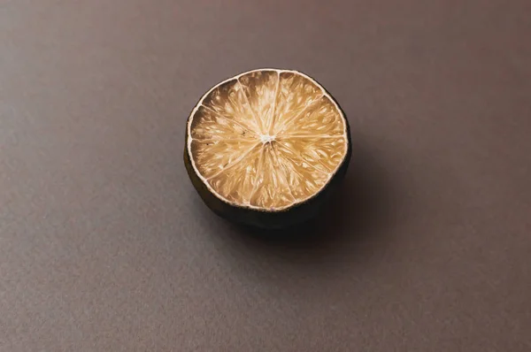 The concept of ugly fruits and citrus fruits. Half of sliced lime has dried and deteriorated on a black background. Mold on citrus fruits. Copy space.