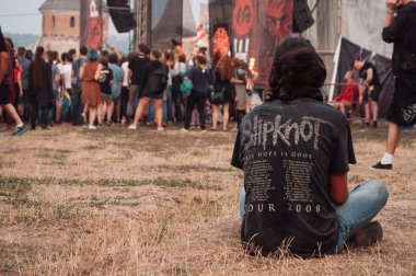 Kamenets, Ukrayna. 9,2013 Kalede rock festivali. Gençler rock müziğe enerjik hareketler yapar. Ön planda bir Slipknot t-shirt uzun saçlı bir adam
