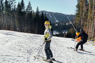 Bukovel, Ukrayna. 2, 2017 Bir kayakçı bir dağın yamacında kışın güzel güneşli havalarda sürmek. Kız çerçeveye bakarak kayak yapıyor. Tatil köyü ve kayak merkezi Bukovel