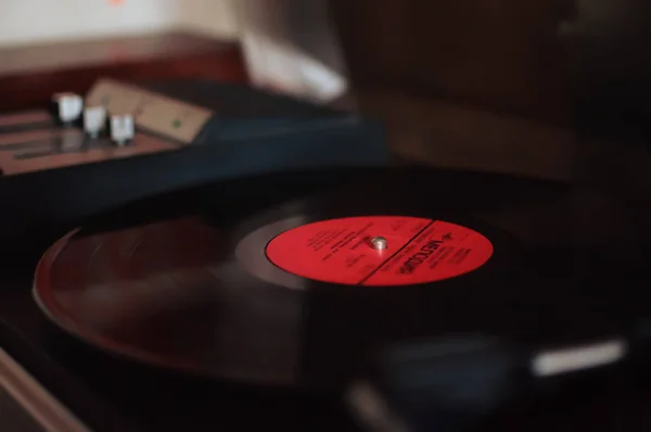 Grabador de vinilo sobre fondo de atardecer sobre las luces de la ciudad. Tecnología de sonido para DJs para mezclar y reproducir música. Un disco de vinilo negro. 1980 vinilo vintage tocadiscos de madera. Aguja de registro de vinilo —  Fotos de Stock