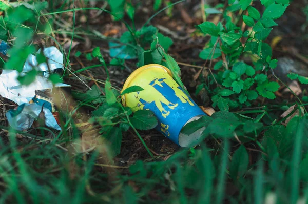 Ένα ποτήρι καφέ και σκουπίδια στο γρασίδι. Ρύπανση του περιβάλλοντος. Περιβαλλοντικό θέμα και καταστροφή. Πράσινο, μηδέν απορρίμματα, σώστε τον πλανήτη, ημέρα της γης, χωρίς πλαστική, ιδέα ανακύκλωσης — Φωτογραφία Αρχείου