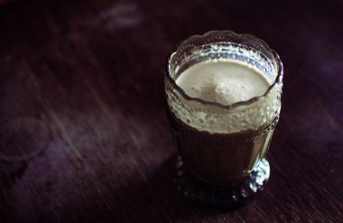 Latte kahve antikdesenleri ile alışılmadık bir bardak. Dokulu ahşap bir masa, vintage tarzı ve yumuşak tonlama üzerinde antika gereçleri Amerikan. Alanı kopyala Üst görünüm.