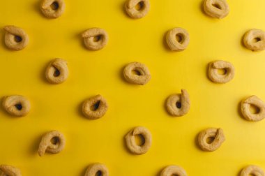 Taralli - Sicilya ve Calabria mutfağında tipik olarak kurutma veya simit benzeri geleneksel bir İtalyan aperatifi. Sarı arkaplan desenli simit. Boşluğu kopyala.