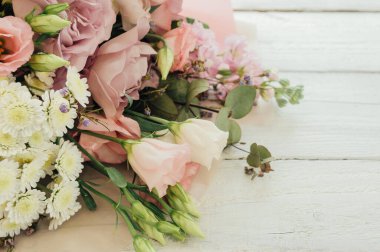 Büyük ve güzel bir buket taze gül, Eustoma, matiola, frezya, okaliptüs, beyaz ve pembe renkli ortanca, Provence tarzında beyaz ahşap bir arka planda. Boşluğu kopyala.