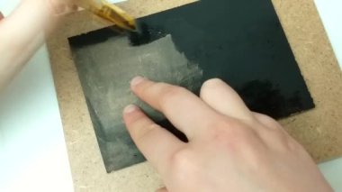 Kız tuvali siyah guaj boyasıyla boyuyor. Metin yazmak için el yapımı tablet.