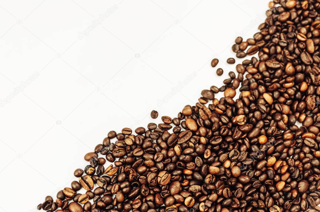 Coffee beans are scattered over the surface on a blank white background. a handful of brown coffee beans. Coffee background with copy space for lettering, text or logo. Mock up.