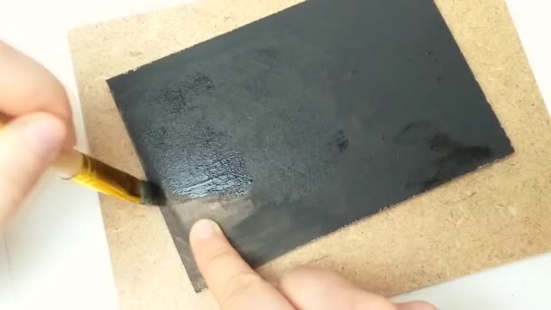 Het meisje uploadt een doek met zwarte gouache verf. Handgemaakte tablet voor het schrijven van tekst. — Stockvideo