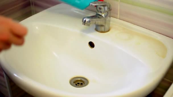 Flicka i blå latexhandskar häller tvättmedel i handfatet i badrummet. Begreppet renlighet. — Stockvideo