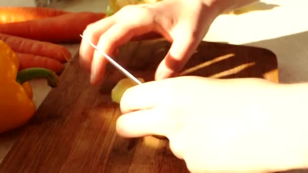 En una tabla de cortar de madera, el cocinero corta tubérculos de papa crudos con un cuchillo. Las manos femeninas sostienen un cuchillo afilado y cortan papas para sopa. — Vídeos de Stock
