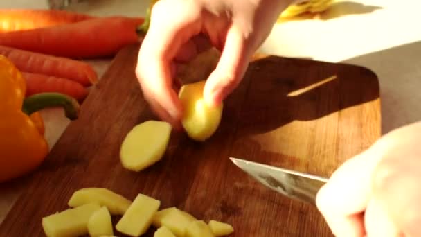 在一块木板上，厨师用一把刀切生土豆块茎。女手拿着一把锋利的小刀和薯片做汤. — 图库视频影像