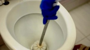 Mavi eldivenli kız banyoyu yıkıyor, tuvaleti temizliyor. Tuvalette temizlikçi olarak çalışıyorum. Temizlik ve temizlik için tuvaleti fırçala. Tuvaleti temizliyorum. Temizlik hizmeti kavramı